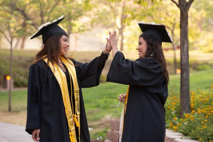 Two students at convocation giving each other a high five