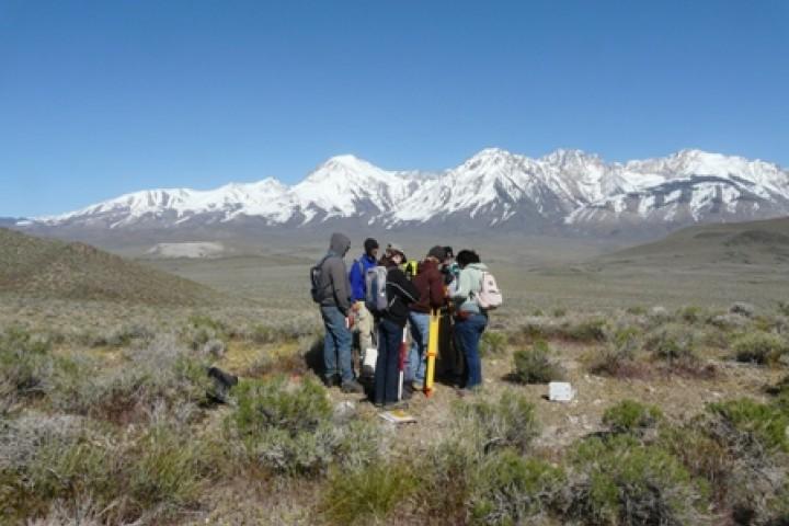 Group of students standing in a field with mountains in the background